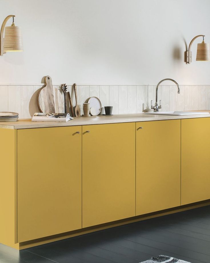 a kitchen with yellow cabinets and white walls