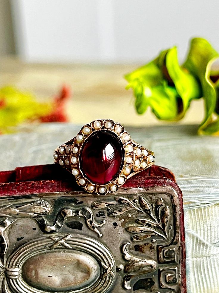 Antique Victorian garnet and pearls ring. The garnet is juicy and cabochon cut, perfect condition. The split seed pearls are all in great condition. DETAILS: Dimensions: size 7 - 3,7gr Hallmark: no hallmarks - tested 14ct gold Condition: Excellent All the items are carefully packaged with upcycled materials and ready to be gifted! Friendly layaway plans are always possible! Please DM for the details. You can message me in English, Italian or French! Thank you for visiting my shop, come and see m Antique Victorian Ring 1stdibs, Antique Garnet Ring, Pearls Ring, Antique Rings Victorian, Georgian Ring, Seed Pearl Ring, Demantoid Garnet, Jewelry Chest, Upcycled Materials