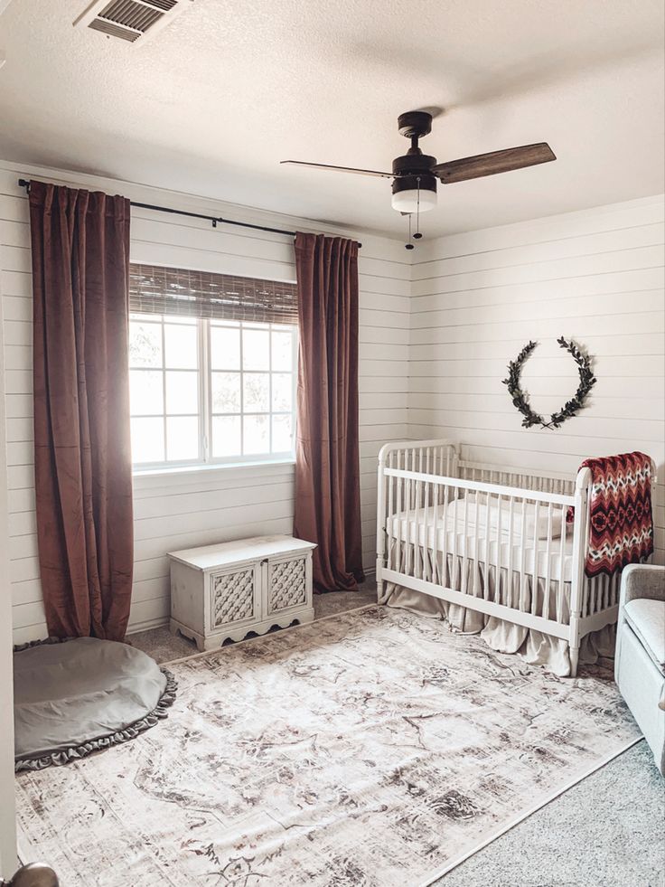 a baby's room with a white crib and brown drapes