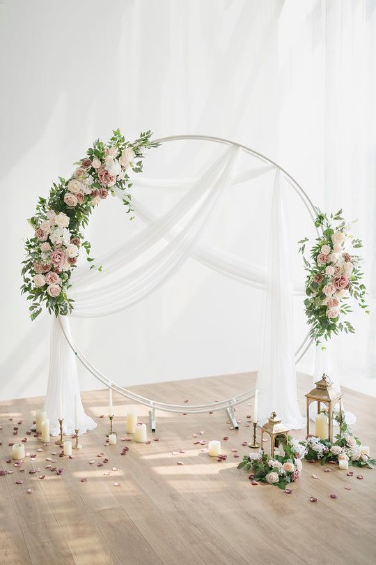 a wedding arch with flowers and candles on the floor in front of white backdrops