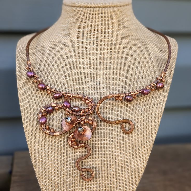 a necklace on a mannequin is adorned with copper beads and pink glass beads