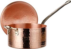 a copper colored pot with a lid and spoon