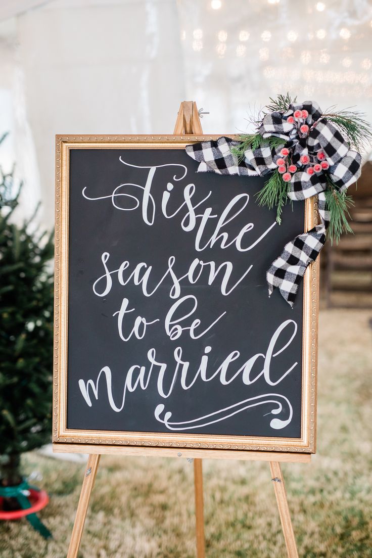 a chalkboard sign that says it's the season to be married and decorated with greenery