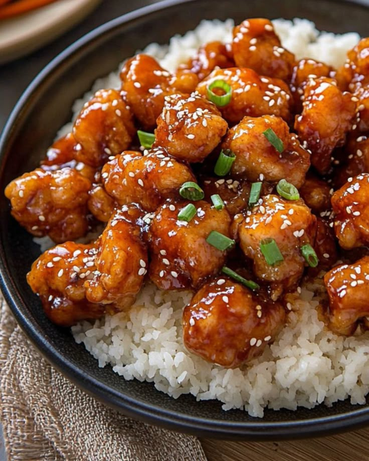 a black plate topped with rice and chicken