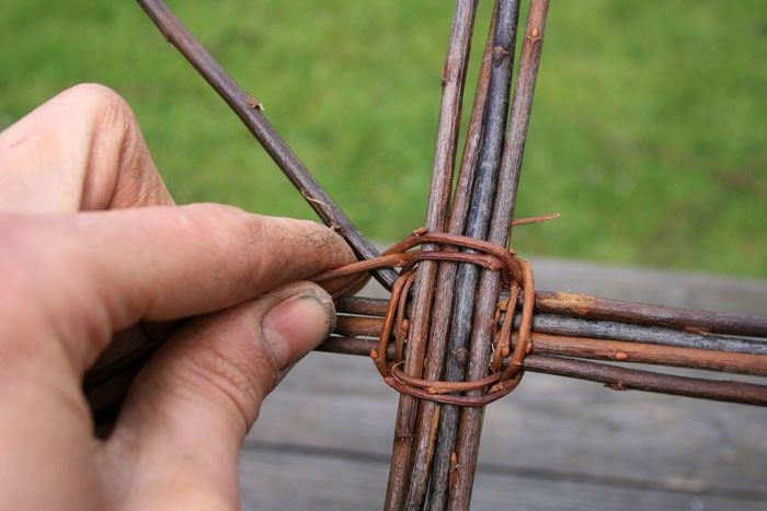 a person is making a piece of wood with sticks and some kind of wire attached to it