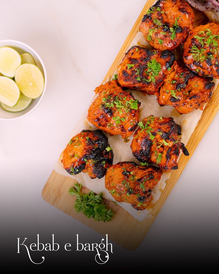 a wooden cutting board topped with chicken wings next to a bowl of sliced lemons