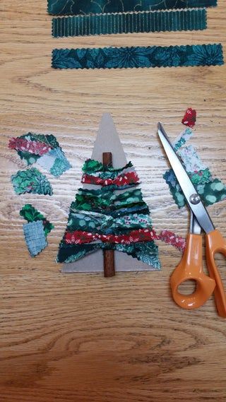 a pair of scissors sitting on top of a wooden table next to strips of fabric