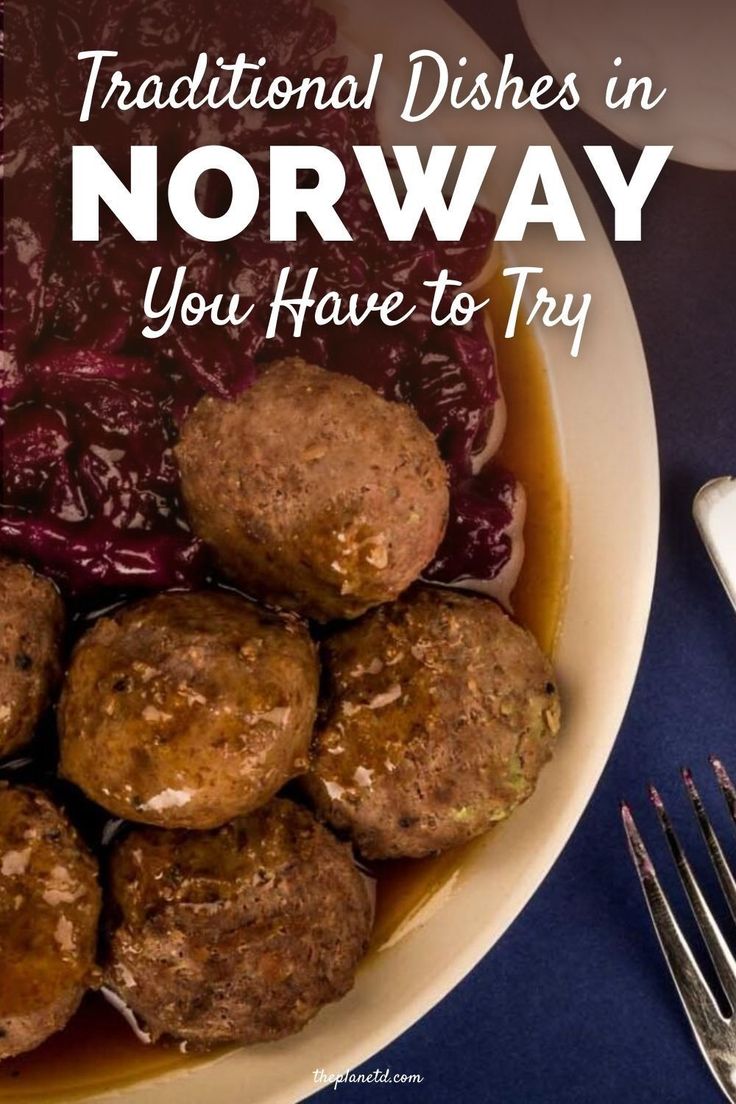 a bowl filled with meatballs covered in sauce next to a fork and knife on a blue table cloth