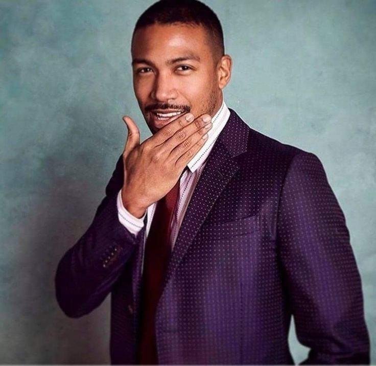 a man in a suit and tie posing for the camera with his hand on his mouth