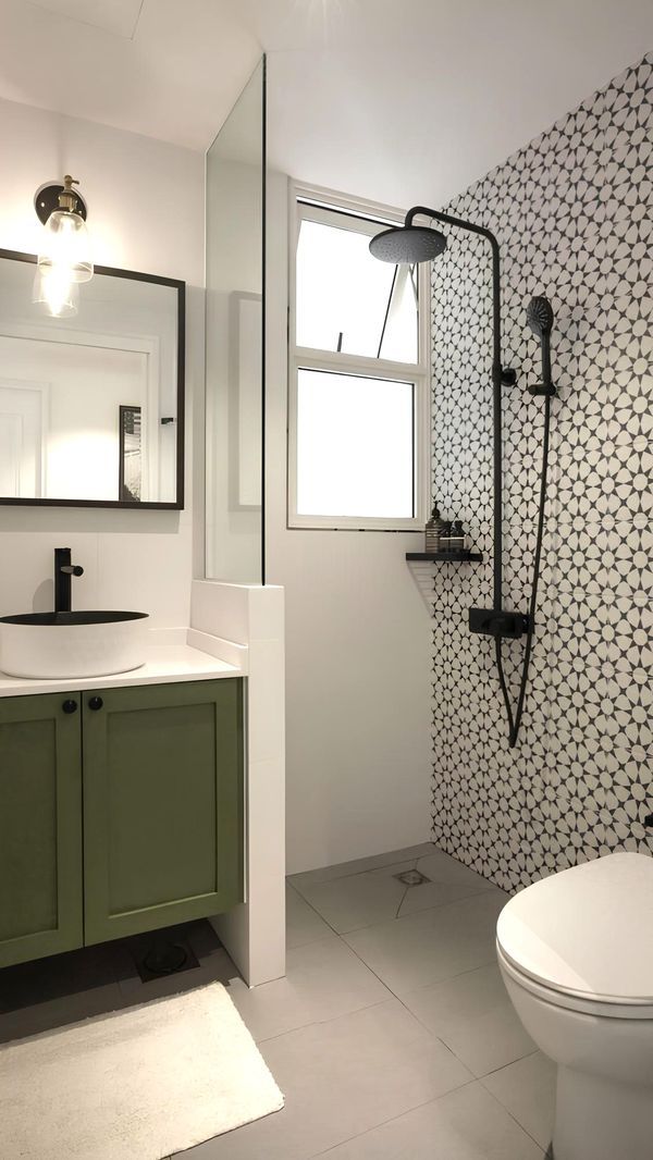 a white toilet sitting next to a green sink in a bathroom under a mirror and light