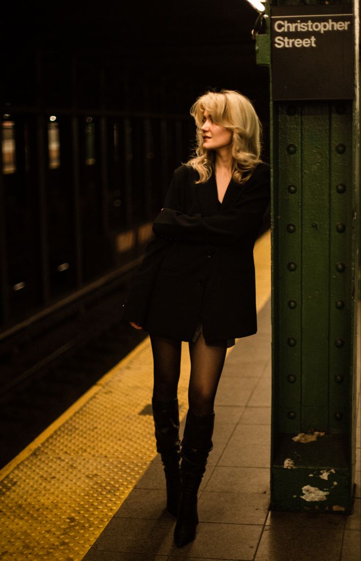 a woman is standing next to a train platform