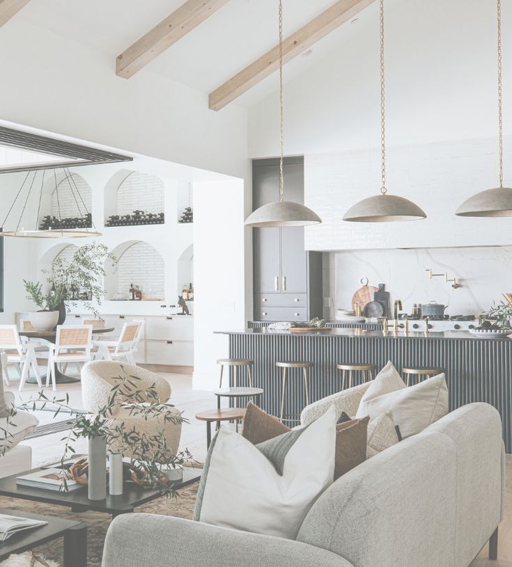 a living room filled with furniture next to a kitchen and dining room table in front of a window