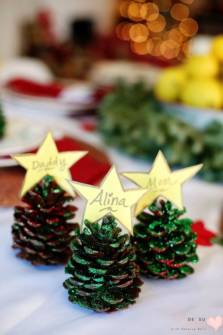 three small pine cones sitting on top of a table covered in christmas decorations and trees