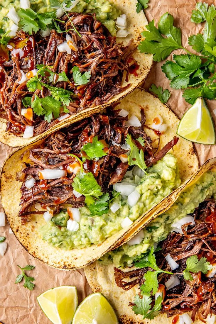 three shredded beef tacos with guacamole and cilantro on top