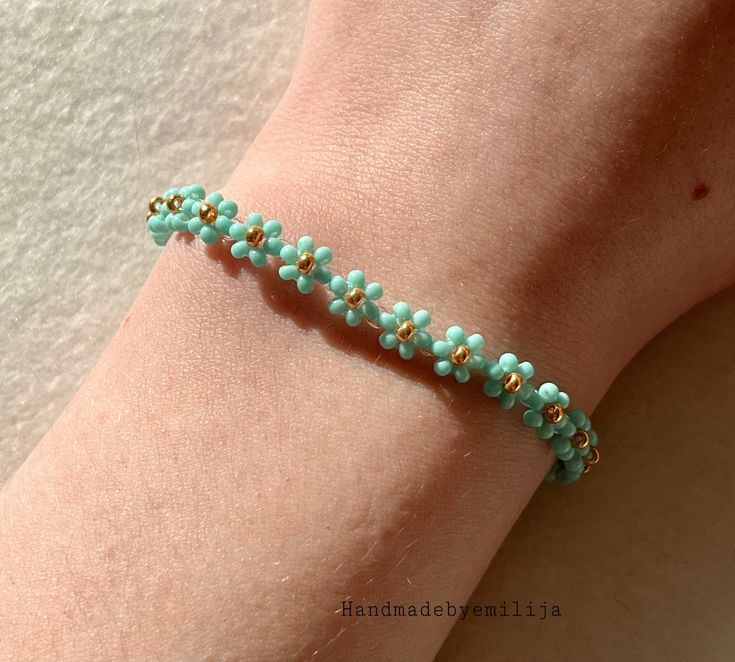 a woman's arm wearing a bracelet with turquoise beads and gold accents on it