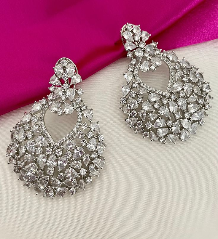 Diamond Earrings to shine with elegance and grace! Adorn these gleaming CZ earrings and capture the essence of timeless sophistication.  The clip back gives additional support. Details: Earrings Length-2.5 Inches Weight of Each Earring-25 grams All products are manufactured using traditional skills from our rich heritage of crafts.  The process of these crafts is essentially manual. Hence, any irregularities or variations are an inherent part of these handcrafting processes. Hand Set Hoop Earrings For Party, Diamond Hand-set Earrings For Party, Party Hand Set Diamond Drop Earrings, Celebration Diamond Drop Earrings, Party Hand Set Cubic Zirconia Chandelier Earrings, Hand Set Diamond Drop Earrings For Party, Hand Set Diamond Earrings For Party, Party Chandelier Earrings With Cubic Zirconia, Glamorous Hand Set Drop Earrings