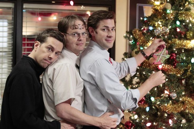 three men standing next to each other in front of a christmas tree