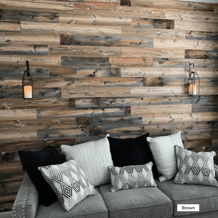 a living room with wooden walls and pillows on the couch, next to a lamp