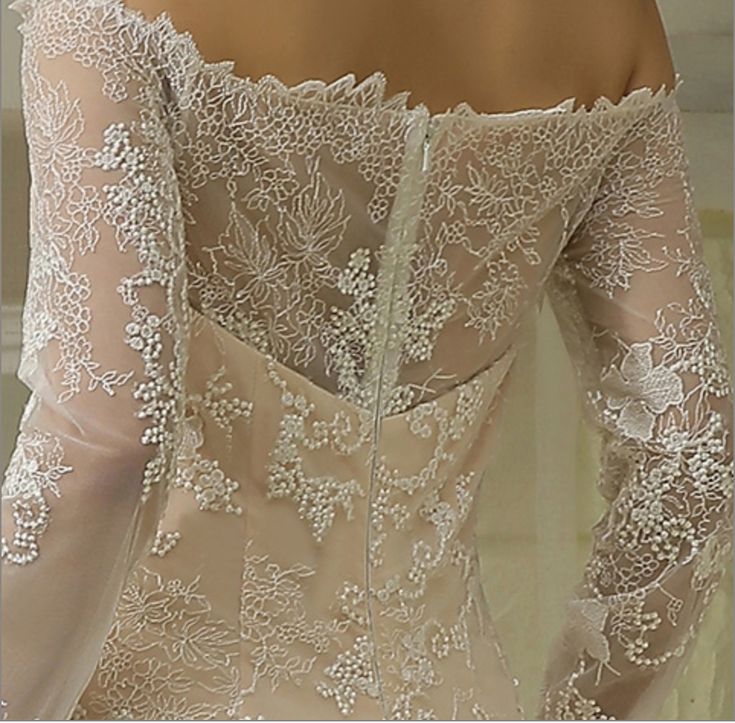 the back of a woman's wedding dress with sheer sleeves and lace on it