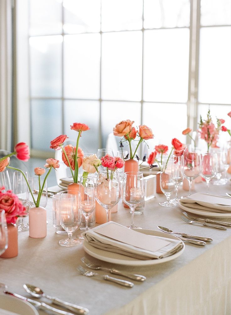 the table is set with flowers in vases and plates