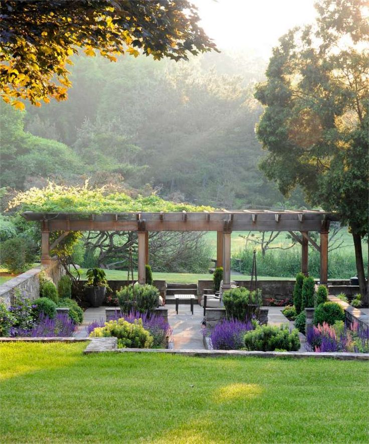 an outdoor garden with benches and flowers in the foreground, surrounded by greenery