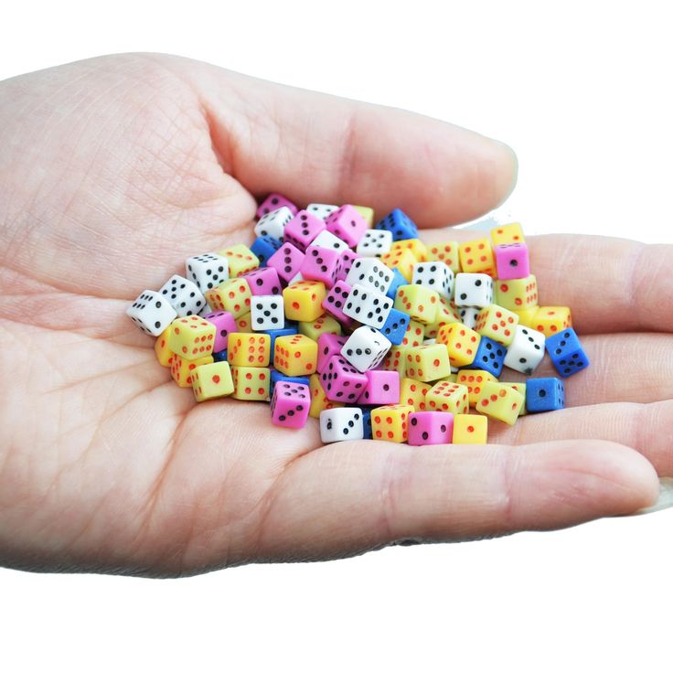 a person's hand holding several small dices