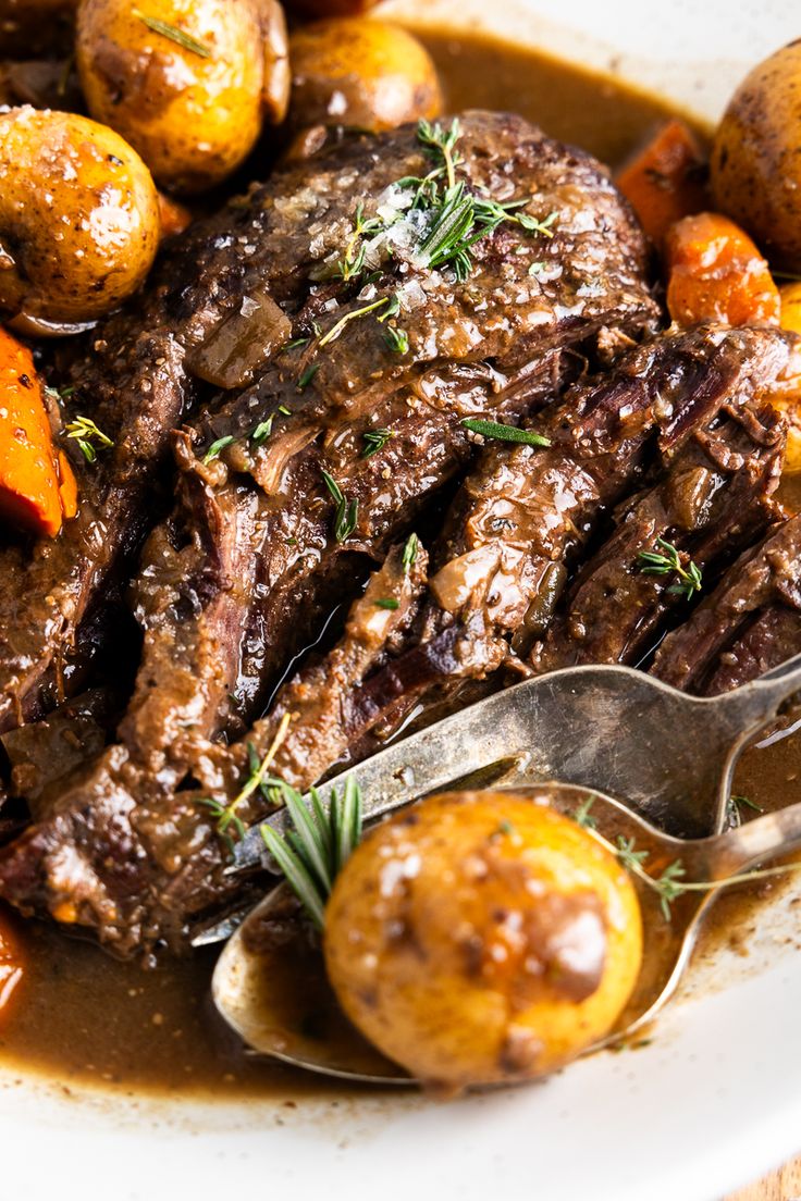 a close up of a plate of food with meat and potatoes on the side next to a spoon