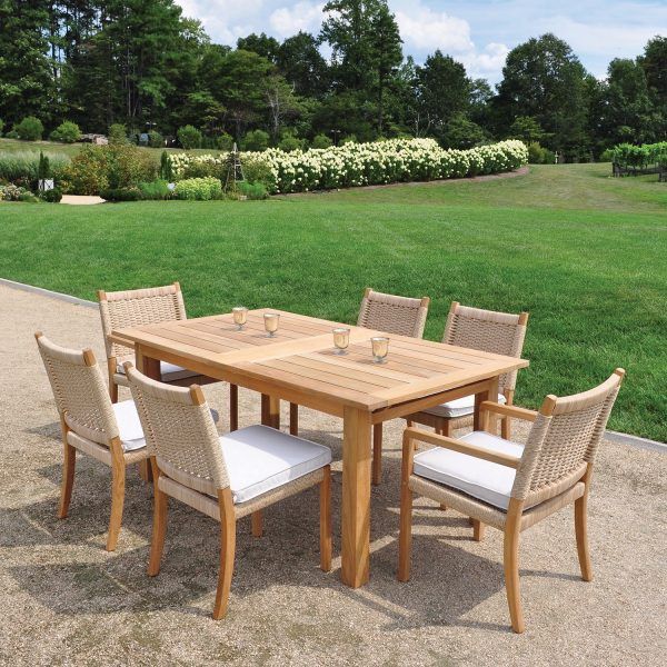 a wooden table and chairs sitting in the middle of a park with grass behind it