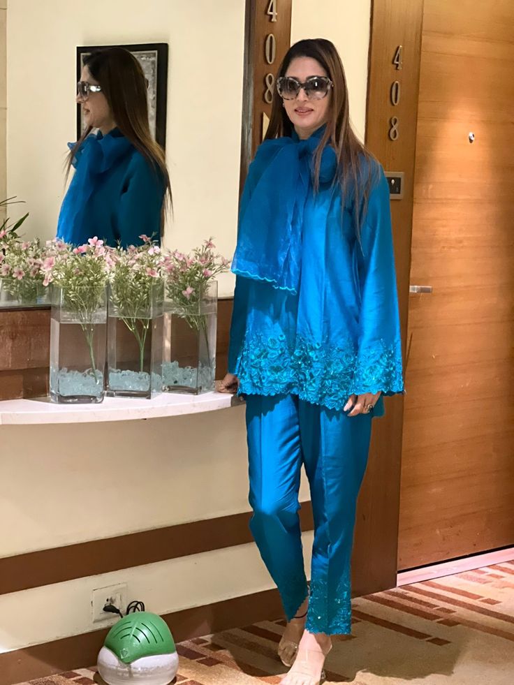 This elegant V-neck embroidered co-ord Set comes handcrafted in a loose-fitting cotton silk fabric laden with embroidery on ghera and sleeves along with embroidered palazzos. Organza stole adds to it elegance. Luxury Long Sleeve Palazzo Set For Eid, Luxury Long Sleeve Sets With Embroidered Border, Luxury Formal Sets With Embroidered Border, Luxury Blue Palazzo Set For Eid, Luxury Indigo Sets For Festive Occasions, Luxury Straight Pants Set For Eid, Luxury Elegant Palazzo Set For Eid, Luxury Sets With Straight Pants For Diwali, Luxury Festive Sets With Embroidered Sleeves