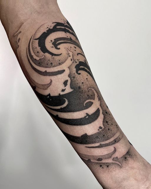 a man's arm with a black and white swirl tattoo on the left forearm