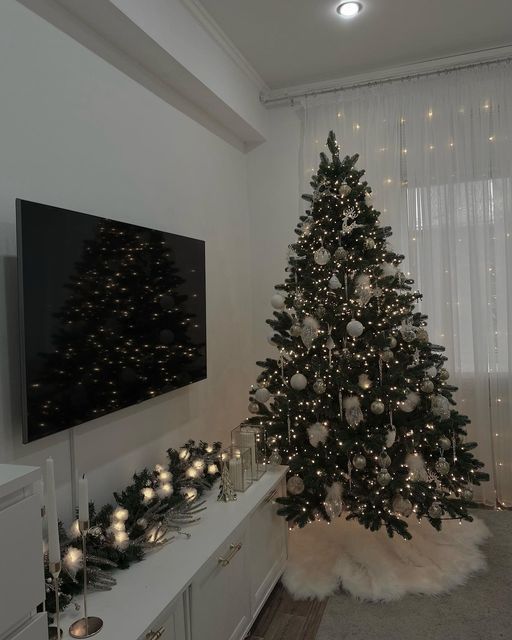 a living room with a christmas tree in the center and lights on the wall behind it