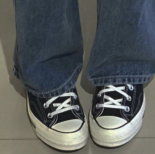 a person wearing blue jeans and black sneakers