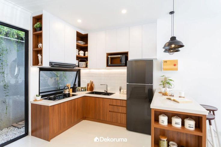 a kitchen with white walls and wooden cabinetry has a glass door leading to the outside