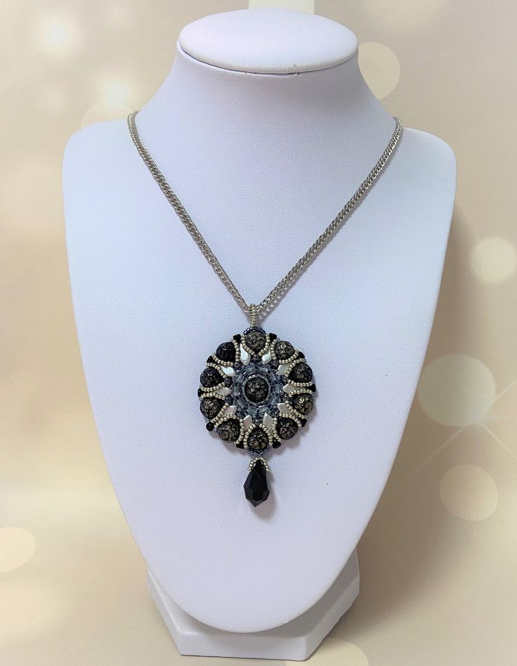 "Baroque style black and silver circle pendant necklace. This boho pendant necklace is fashioned with glass beads in shades of black and silver atop a Baroque style cabochon.  Highly glamorous and visibly vintage-inspired, this opulent creation will add a touch to your outfit needs. ✧ MEASUREMENTS ✧ Chain Length: 22.45\"  (57cm) Pendant Diameter: 1.65\" (4.2cm) Pendant  Height (including drop): 2.36 (6cm) ✧ MATERIALS ✧ ♦ Lovingly handmade using a needle and FireLine beading thread ♦ Made from Kite beads, Minos beads, Fire Polish beads ♦ Metals are either golden, silvery, or bronze-colored ✧ CARE INSTRUCTIONS ✧ To maintain the beauty of your Liora Jewelry piece, please avoid contact with any liquid (water, perfume, cleaning detergents, etc.) and avoid sleeping, showering, or exercising with Silver Necklaces With Round Pendant And Beaded Chain, Black Metal Necklace With Silver Beads, Black Necklace With Silver Beads, Black Metal Necklaces With Silver Beads, Silver Beaded Necklace With Black Beads As A Gift, Silver Beaded Necklaces With Black Beads For Gift, Silver Oval Pendant Necklace For Party, Black Pendant Necklace With Silver Chain, Metal Beaded Pendant Necklace