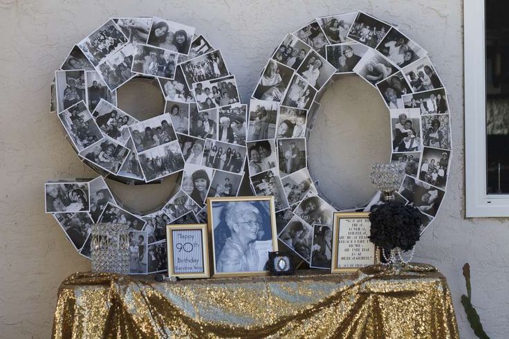 a table topped with pictures and photos next to a wall covered in gold sequins