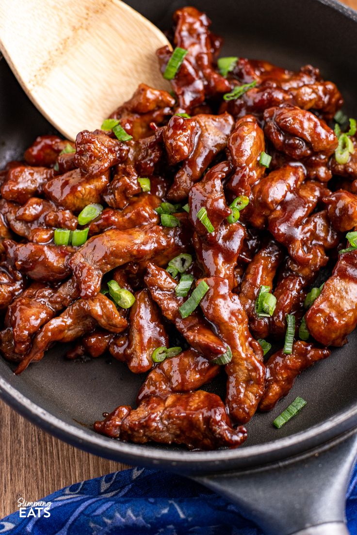 a skillet filled with chicken wings and garnished with green onions