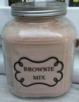 a brownie mix in a glass jar sitting on the ground next to a window