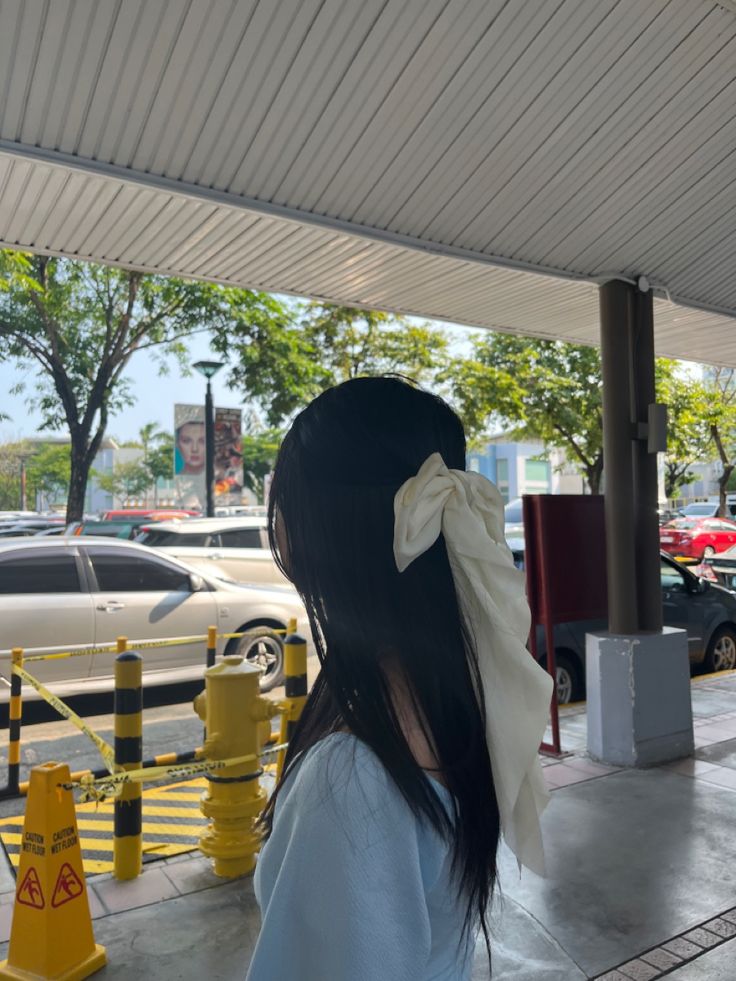 a woman standing in front of a yellow fire hydrant with a bow on her head