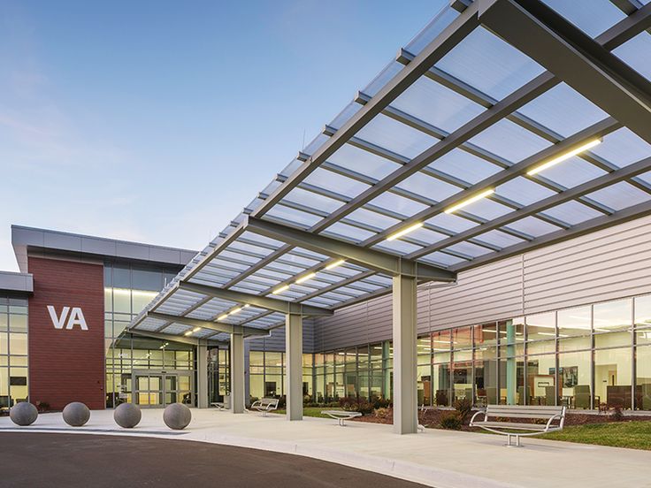 an empty parking lot in front of a building with many windows and benches on the side