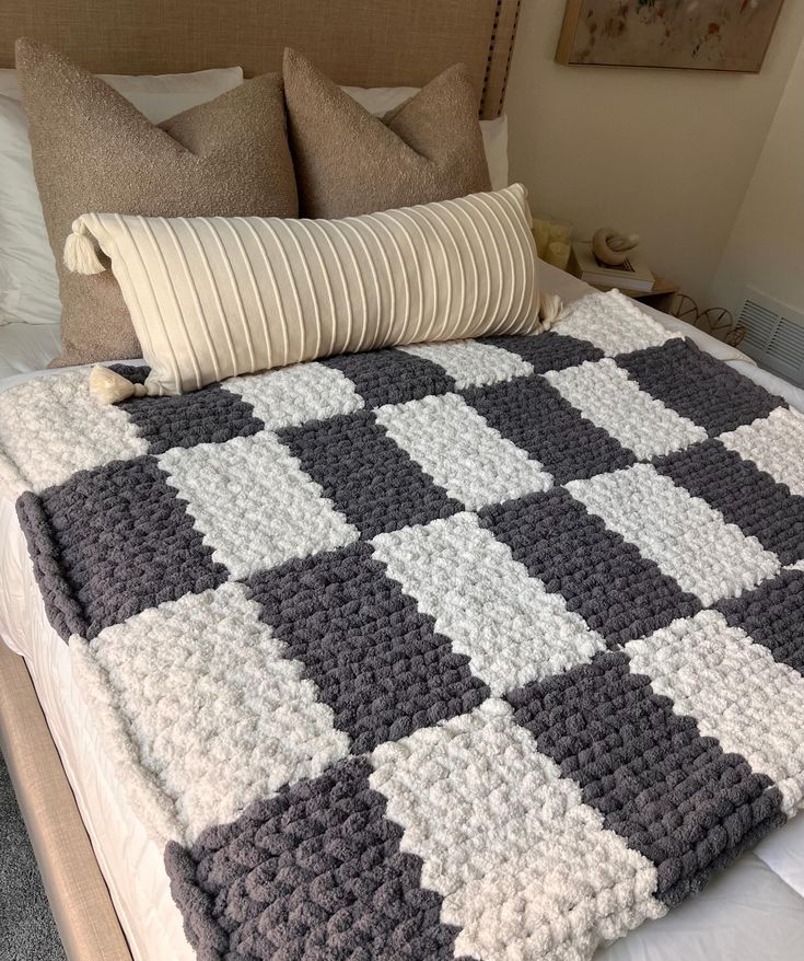 a crocheted blanket sitting on top of a bed next to pillows and blankets