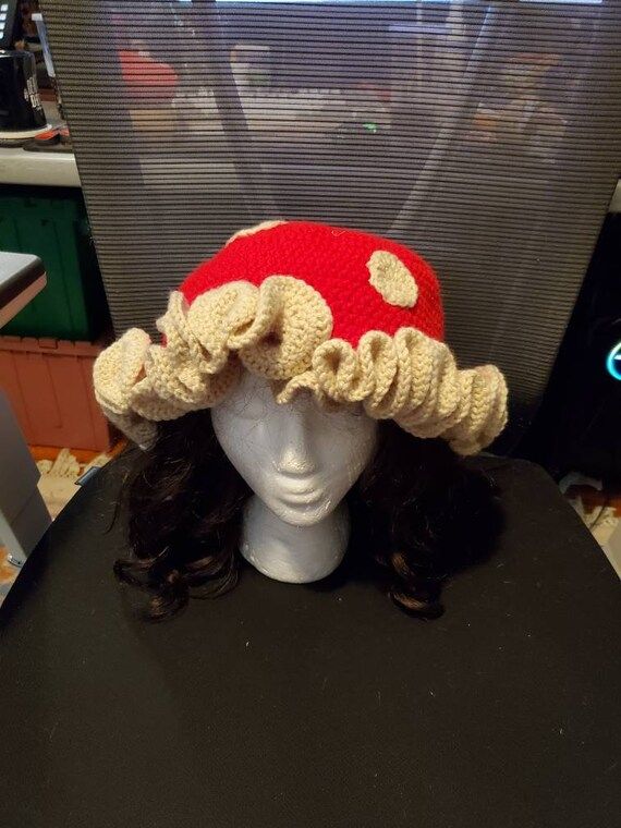 a knitted mushroom hat sitting on top of a white mannequin's head