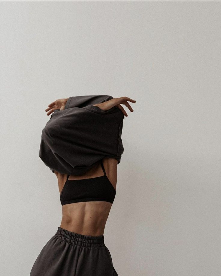 a woman in black sports bra top and shorts with her hands on the back of her head