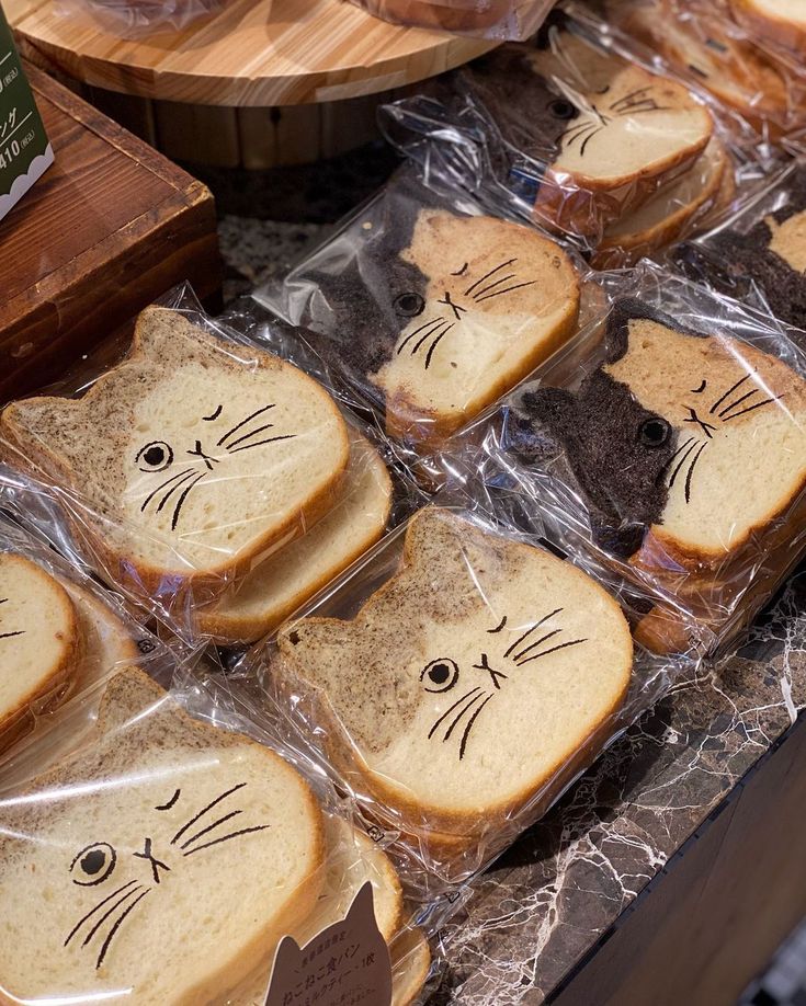 several slices of bread with cats drawn on them sitting in plastic bags next to other food items