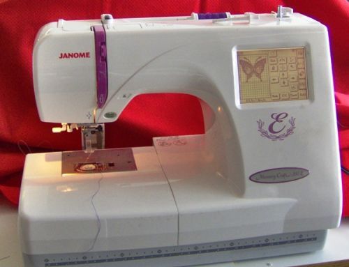 a white sewing machine sitting on top of a table next to a red cloth covered wall