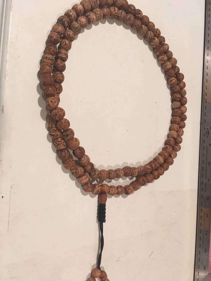 "Bodhi seed mala necklace made of 108 12mm beads with a Bodhi seed guru bead and an adjustable knot that allows you to change the length and tightness of the beads. Bodhi seeds are usually not polished so they are a solid color with small ridges or veins. Bodhi in Sanskrit translates to \"enlightened\" or \"awakened,\" therefore the Bodhi seed means \"enlightened seed.\" Bodhi is also a term in Buddhism to reflect a Buddha's understanding of the true nature of things. Many Buddhist wear the Bodh Wooden Beads Necklace For Meditation And Festivals, Wooden Beads Necklaces For Meditation And Festivals, Adjustable Holistic Mala For Meditation, Holistic Necklaces With 8mm Beads For Rituals, Adjustable Spiritual Mala For Puja, Traditional Beaded Bracelets For Meditation With 108 Beads, Bohemian Adjustable Mala For Puja, Adjustable Traditional Mala For Healing, Bohemian Beaded Necklace With 108 Beads For Puja