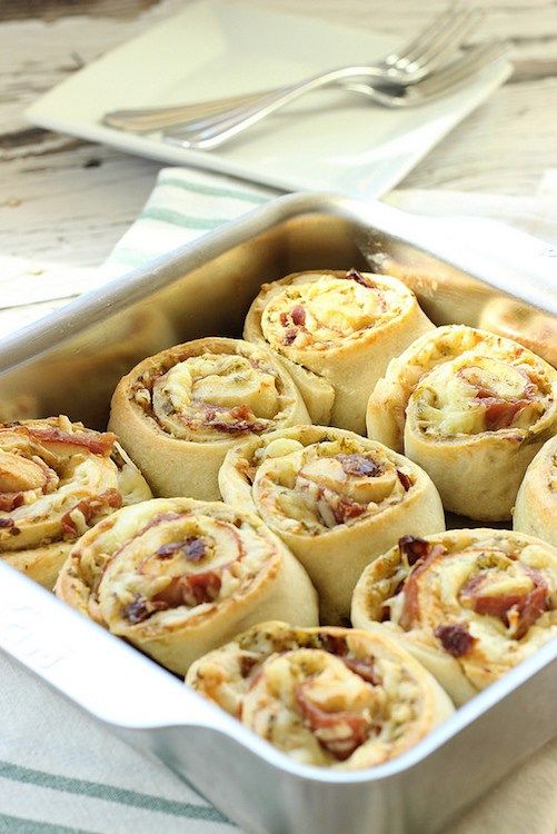 a pan filled with bacon pinwheels sitting on top of a table next to silverware