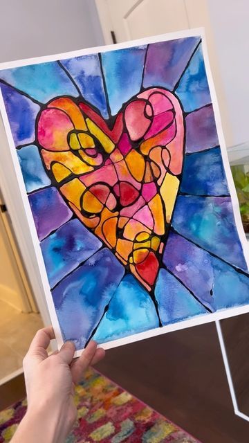 someone is holding up a stained glass heart