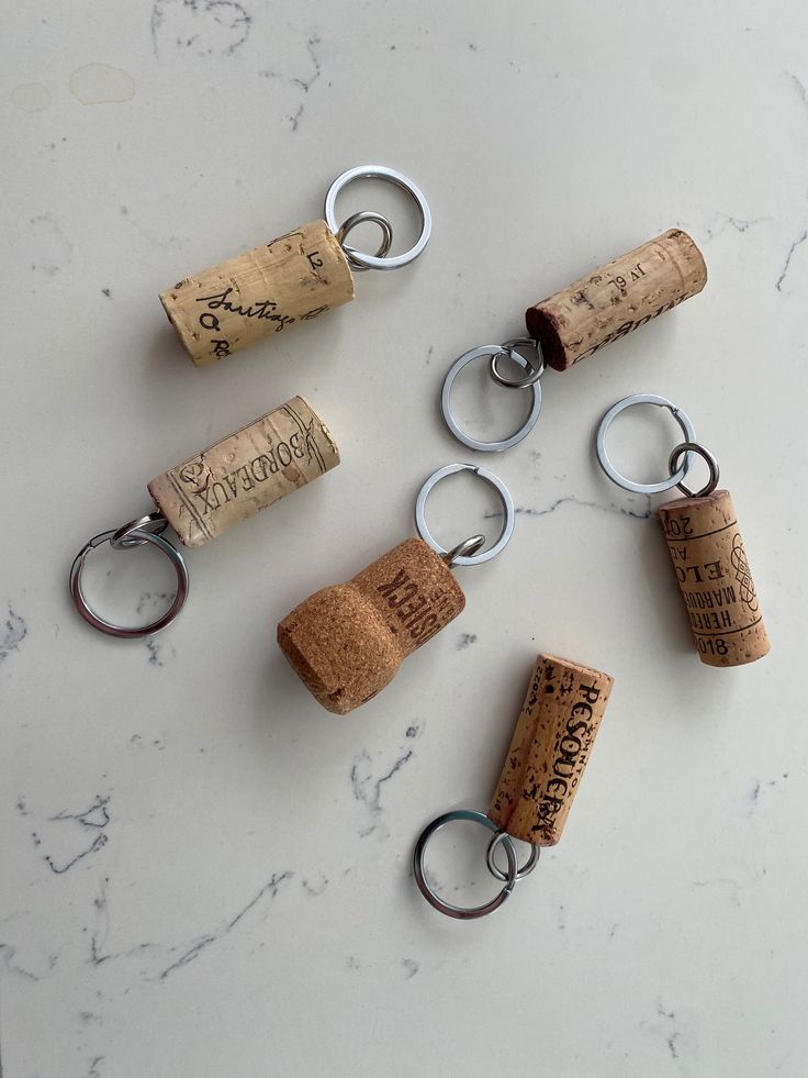 several wine corks are arranged on a marble counter top with key chains attached to them