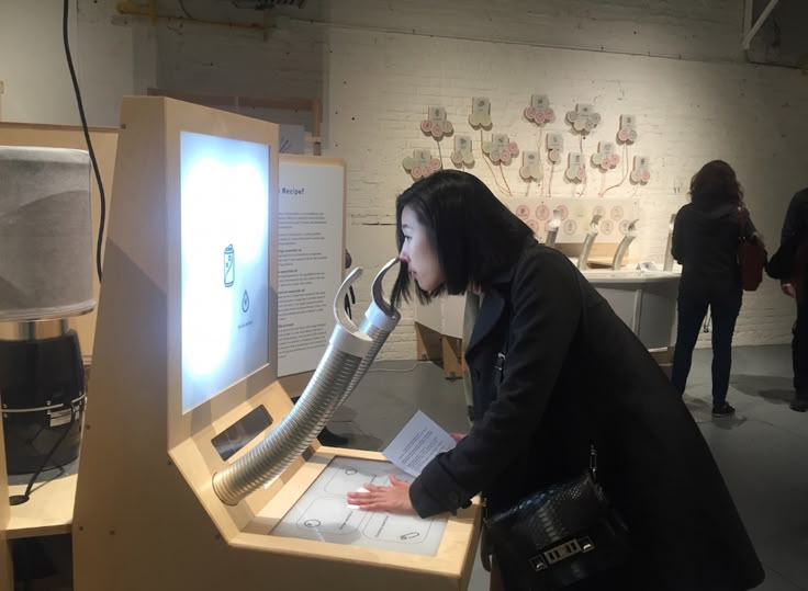 a woman looking at a display in a museum with an old phone on it's stand