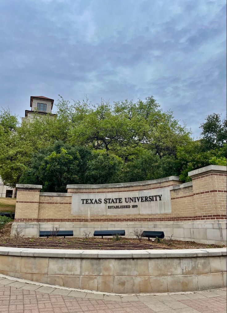 the texas state university sign in front of trees